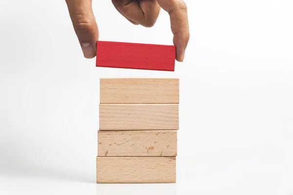 木製のブロックタワーから木製の赤いブロックを追加する人間の手 — ストック写真