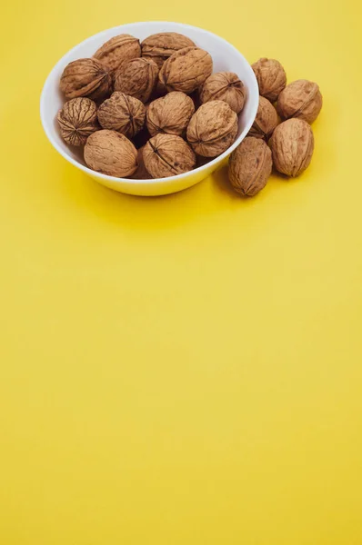 Vertical Shot Walnuts White Bowl Isolated Yellow Background — Stock Photo, Image