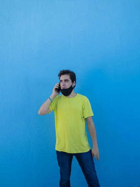 Молодой Европейский Мужчина Желтой Рубашке Медицинской Маске Стоящий Синей Стены — стоковое фото