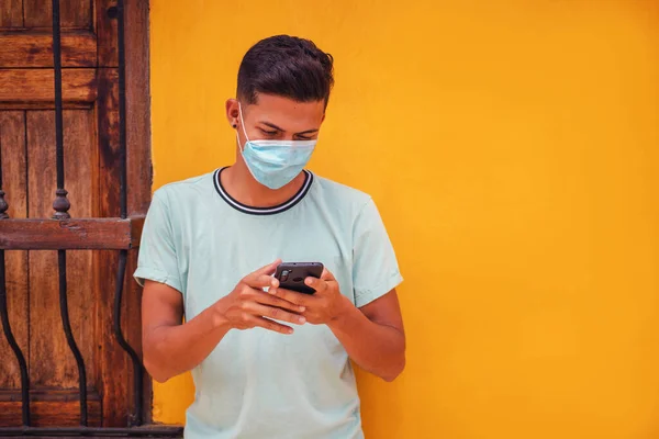 Tânăr Hispanic Mască Care Trimite Mesaje Prin Telefon Mobil Perete — Fotografie, imagine de stoc