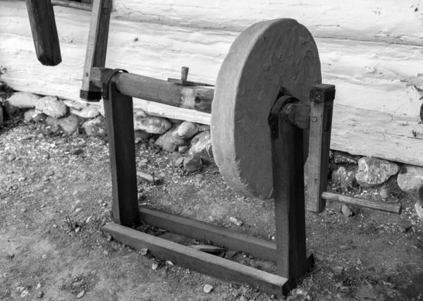 A grayscale shot of an old knife sharpener on the ground at daylight