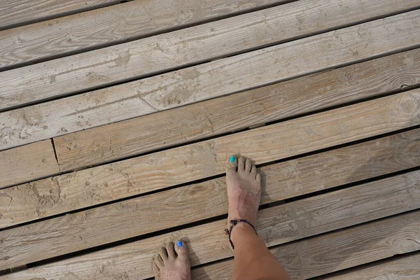 木製の歩道にアンクレット付きの女性の足のトップビュー — ストック写真