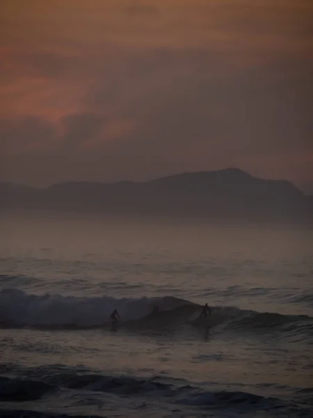 Een Prachtig Schemeruitzicht Een Golvende Zee Met Silhouetten Van Surfmensen — Stockfoto