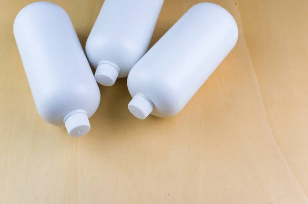 Высокий Угол Съемки Трех Белых Пластиковых Бутылок Светло Коричневой Поверхности — стоковое фото