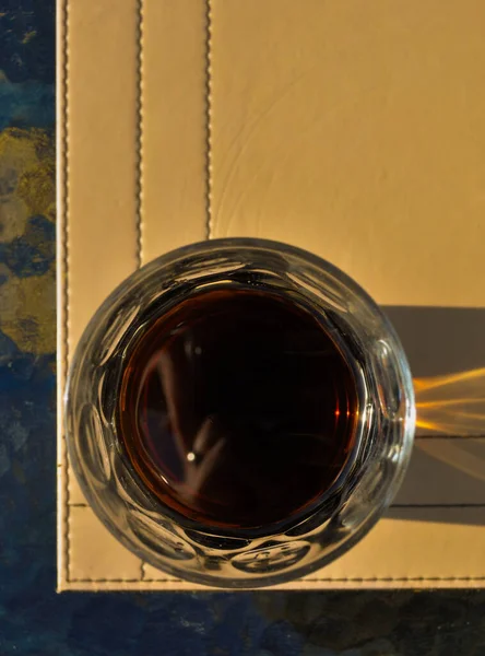 在阳光下的玻璃桌上 在桌垫边上的一杯可乐在头顶上拍的照片 — 图库照片