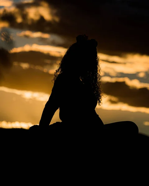 Una Silueta Una Mujer Con Pelo Rizado Sentado Una Roca —  Fotos de Stock