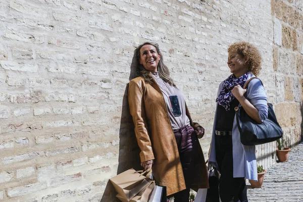 两个拿着购物袋在街上聊天的快乐的成年女子的照片 — 图库照片