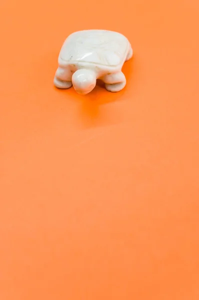 Eine Vertikale Aufnahme Einer Weißen Schildkrötensteinfigur Isoliert Auf Orangefarbenem Hintergrund — Stockfoto
