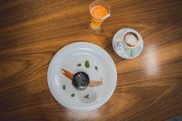 カフェでコーヒーとフレッシュオレンジジュースを提供するダークチョコレートケーキのトップビュー — ストック写真