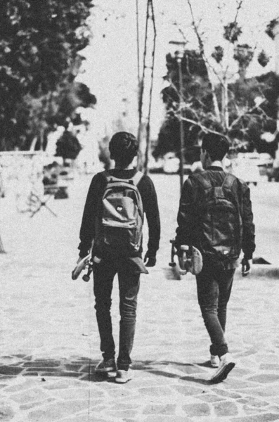 Eine Vertikale Graustufenaufnahme Von Zwei Jungen Die Mit Rucksäcken Die — Stockfoto