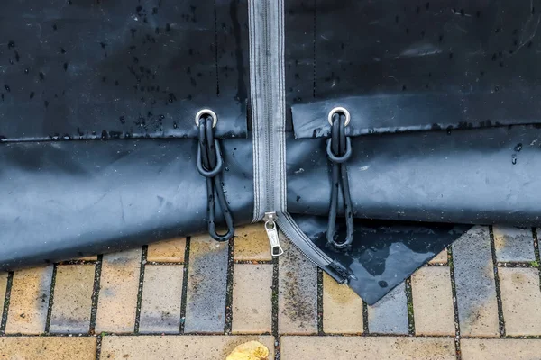 A bottom of a big tent with a zipper on the ground