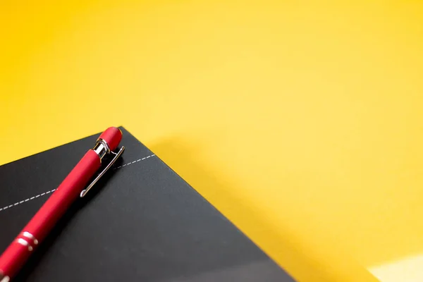 黄色の背景に隔離されたノートとペンのクローズアップ — ストック写真