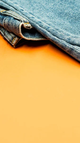 Turuncu Bir Yüzeyde Bir Kot Pantolonun Dikey Görüntüsü — Stok fotoğraf