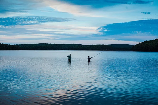 青い空の下の穏やかな湖で二人の男釣り — ストック写真