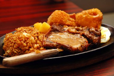 Soğan halkalı biftek ve cızırdayan tabakta pirinç.