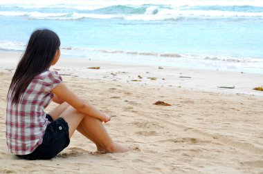 Filipinler, Palawan 'da kumsalda oturup düşünen bir kadın.