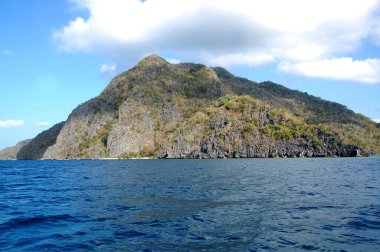 Koron, Palawan, Filipinler 'de kumlu, ağaçlı ve mavi sulu kireçtaşı oluşumu