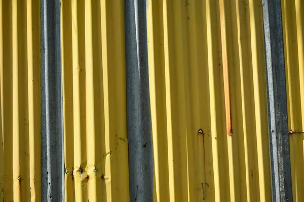 Metal sheet yellow corrugated barrier use to set up a perimeter wall on construction site or vacant lot