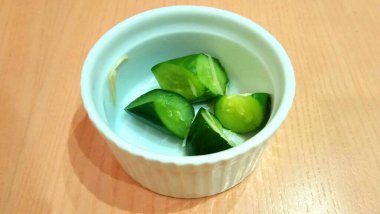 Restoran menüsünün küçük kasesinde servis edilen küçük dilimlenmiş yeşil salatalık.