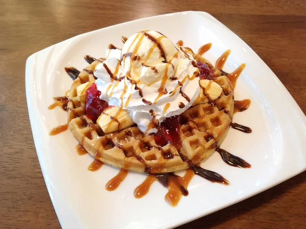 Muz, krema, dondurma, çilek reçeli ve waffle tatlı menüsünün üstüne de şurup.