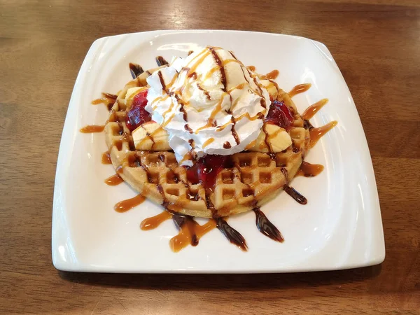 Muz, krema, dondurma, çilek reçeli ve waffle tatlı menüsünün üstüne de şurup.