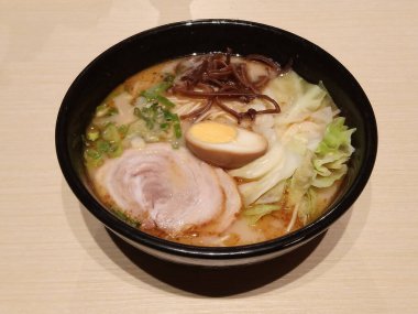 Japon restoranının siyah kasesinde erişteli sebze, domuz eti, yumurta ve çorba.