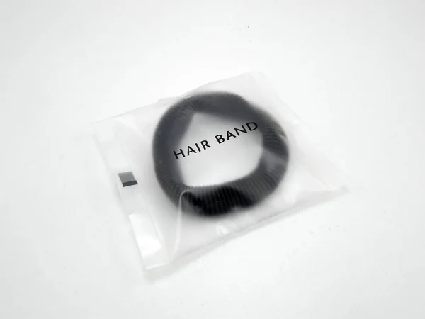 人の長い髪を結ぶために使用するプラスチック製のラッパーに置かれた黒い髪のバンド — ストック写真