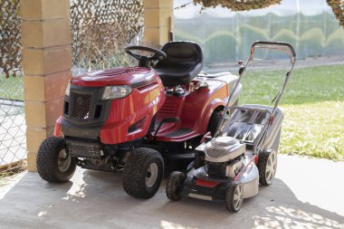 evin bahçesinde yaz aylarında çim biçme makinesi kırmızı ve gümüş iki model
