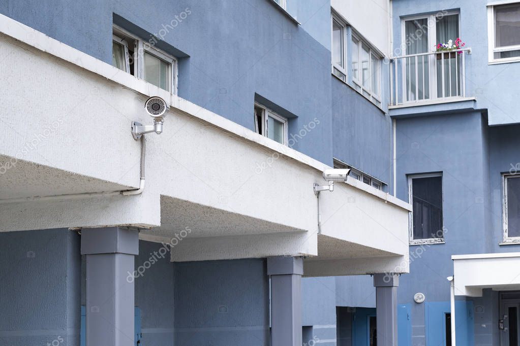 outdoor surveillance camera on a blue white wall of an apartment building in a residential area of the city during the day