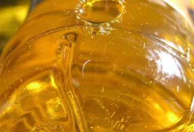 Berrak bir plastik şişe sarı berrak güneş yağı hava kabarcıkları. Yağ tembel akar ve güneşte parıldamak, atlamak ve hava molekülleri kadar küçük ve büyük şişirilmiş kabarcıklar dörtnala yanında. 