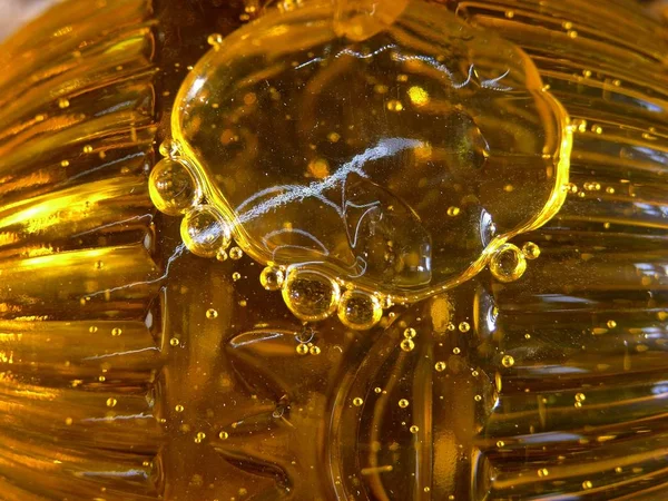 Berrak bir plastik şişe sarı berrak güneş yağı hava kabarcıkları. Yağ tembel akar ve güneşte parıldamak, atlamak ve hava molekülleri kadar küçük ve büyük şişirilmiş kabarcıklar dörtnala yanında. 