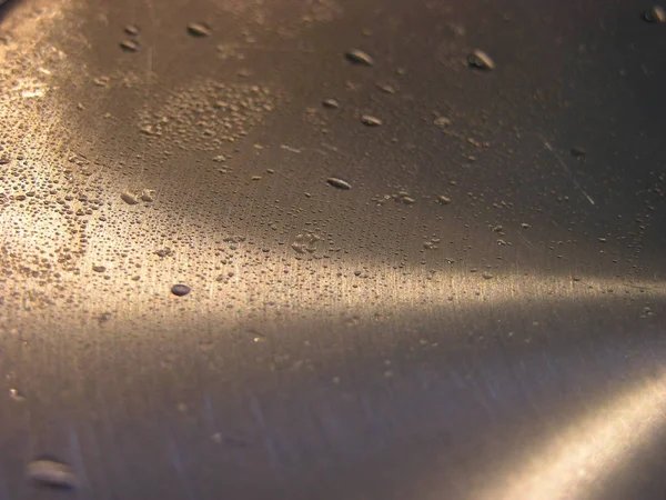 Metal sıcak kapak tavadan, yoğuşma ile kaplı. Bu gaz sobası üzerinde kaputtan lamba ışınları parlayan, pişirme buhar ile damlama olduğunu. metal üzerinde hemisperik bantlar vardır. Makro. Arka plan dokusu. Yumuşak odaklama.