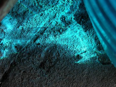 Kimyasal mavi sıvının betonunda parlak fosforlu mavi parıltı var. Odanın karanlık köşesinde. arkaplan, doku.