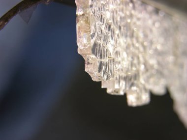 Karanlığın içinde asılı duran ağır bir kristal, düşmeye ve delmeye hazırdı. Renksiz, kaderin kurban silah kayıtsız (alegorik). kırık temperli cam yakın çekim. sığ odak.