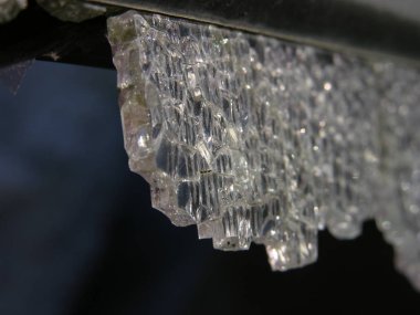 Karanlığın içinde asılı duran ağır bir kristal, düşmeye ve delmeye hazırdı. Renksiz, kaderin kurban silah kayıtsız (alegorik). kırık temperli cam yakın çekim. sığ odak.