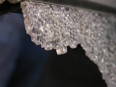 Karanlığın içinde asılı duran ağır bir kristal, düşmeye ve delmeye hazırdı. Renksiz, kaderin kurban silah kayıtsız (alegorik). kırık temperli cam yakın çekim. sığ odak.