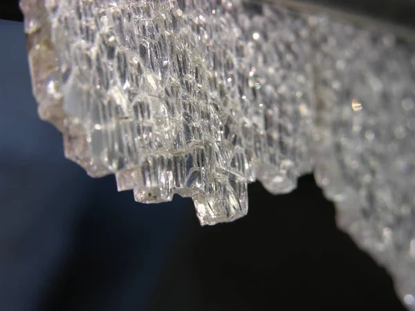 Karanlığın içinde asılı duran ağır bir kristal, düşmeye ve delmeye hazırdı. Renksiz, kaderin kurban silah kayıtsız (alegorik). kırık temperli cam yakın çekim. sığ odak.