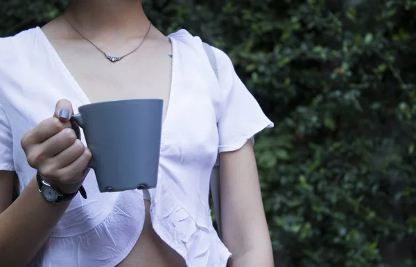 Attrappe einer weiblichen Hand, die eine Kaffeetasse auf einem natürlichen Garten hält — Stockfoto
