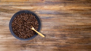 İzole edilmiş ahşap arka planda koyu kahve fincanında kahve çekirdekleri