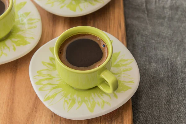 Tahta üzerinde duran Türk kahvesi. Arka planda gri kapak