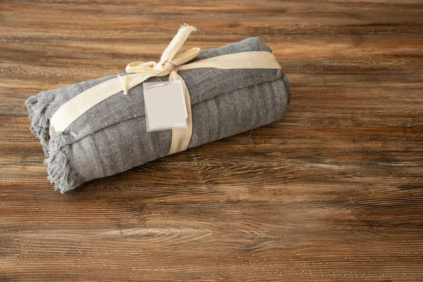 rolls of cotton grey towel, with label mockup, isolated on wooden background.