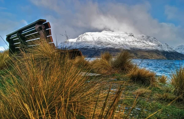 Banco de madera junto al río y las montañas nevadas en el fondo en Queenstown Nueva Zelanda — Foto de Stock