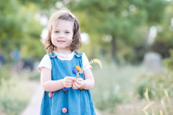 Leende Liten Flicka Gammal Bär Trendiga Denim Klänning Hålla Blomma — Stockfoto