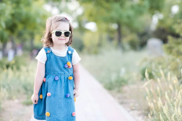 Смешная Девочка Лет Солнцезащитных Очках Джинсовом Платье Прогуливаясь Парку Природе — стоковое фото