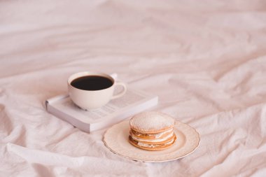 Açık bir kitaptaki taze kahve, beyaz tabakta krep ve yakın plan çekimde. İyi sabahlar. Seçici odak. 