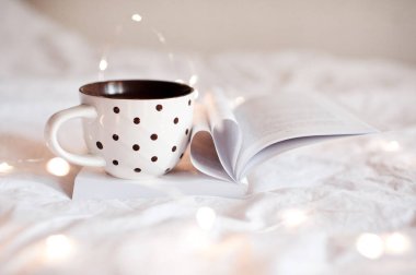 Geceleri, kalp şeklinde sayfaları katlanmış, açık bir kitap üzerine bir fincan çay. Günaydın.. 