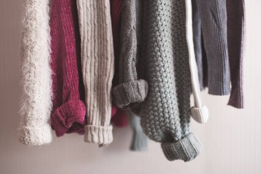 Katlanmış kolları olan örgü elbiseler kapalı mekanda asılı duruyor. Kış mevsimi. 