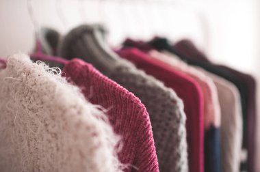 Dükkandaki askılarda örgü süveterler asılı. Seçici odak. 