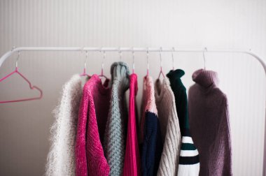 Duvarda örülmüş süveterler olan beyaz askılık. Kış mevsimi. 