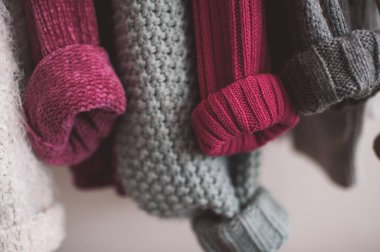 Katlanmış kolları olan örgü elbiseler kapalı mekanda asılı duruyor. Kış mevsimi. 